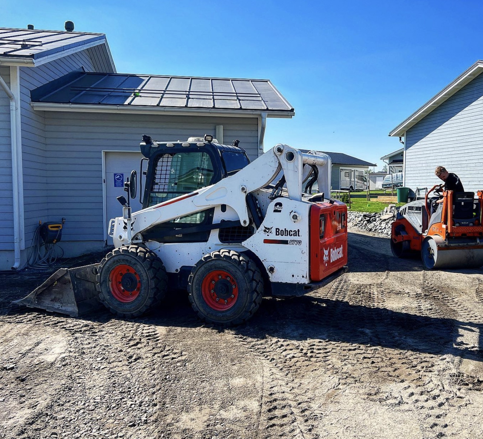 Bobcat ja jyrä omakotitalon pihan pohjatyömaalla