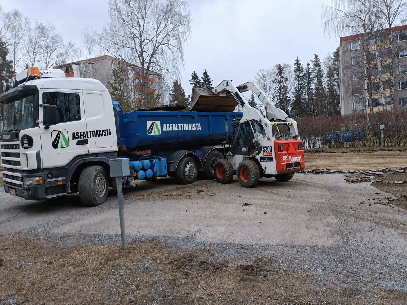 Asfalttikaistan kuorma-auto ja pienkuormaaja maanrakennustyössä